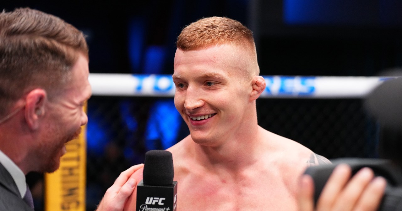 Iwo Baraniewski w klatce UFC, w trakcie walki, z podniesioną ręką po zwycięstwie.