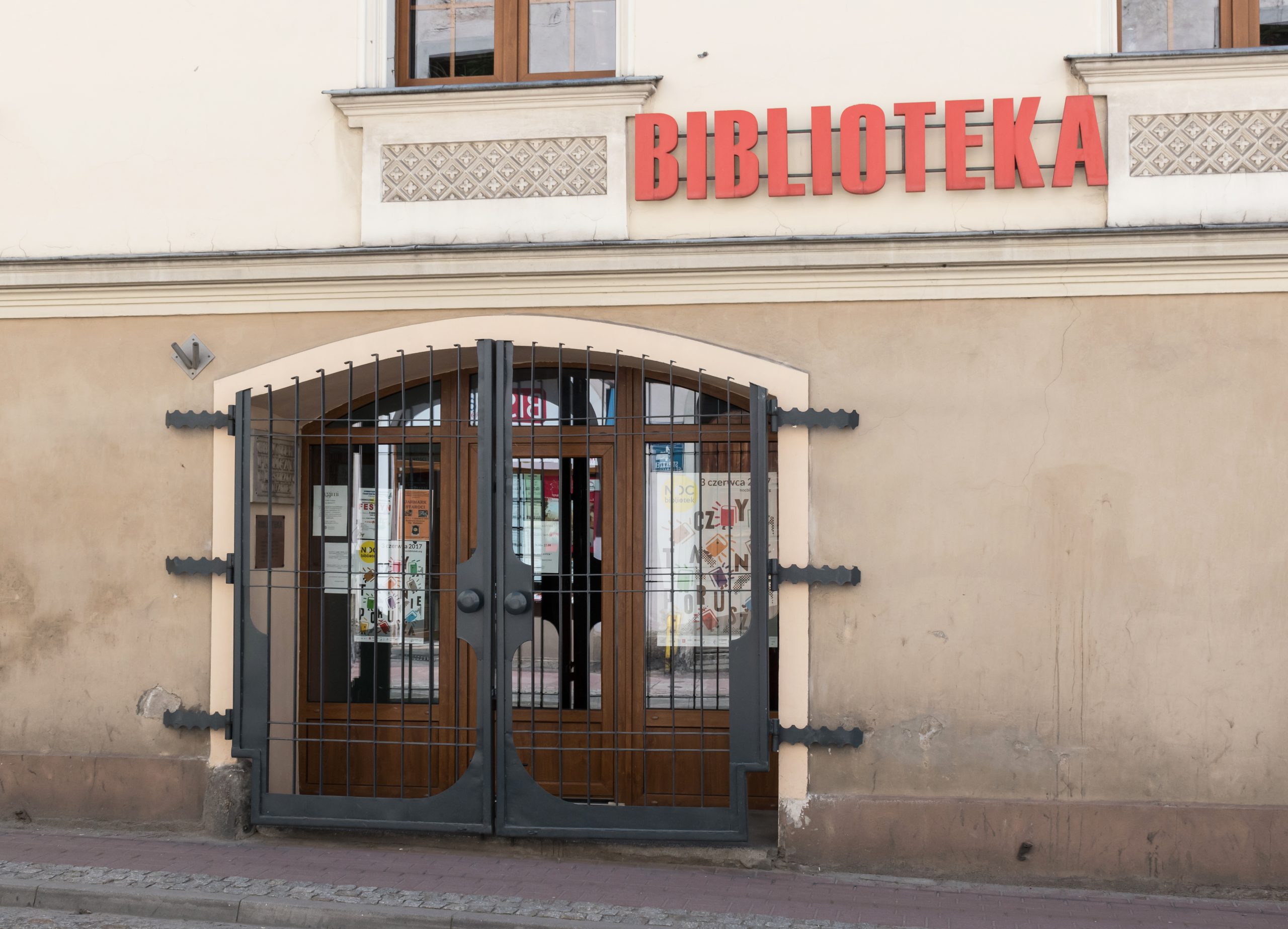Zdjęcie przedstawiające otwartą książkę leżącą na tle półek wypełnionych woluminami w cyfrowej bibliotece, z subtelnym nawiązaniem do danych bibliograficznych.