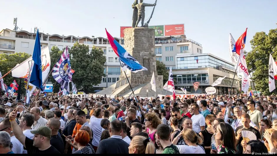 Tłum protestujących ludzi z flagami Serbii na placu w Serbii.