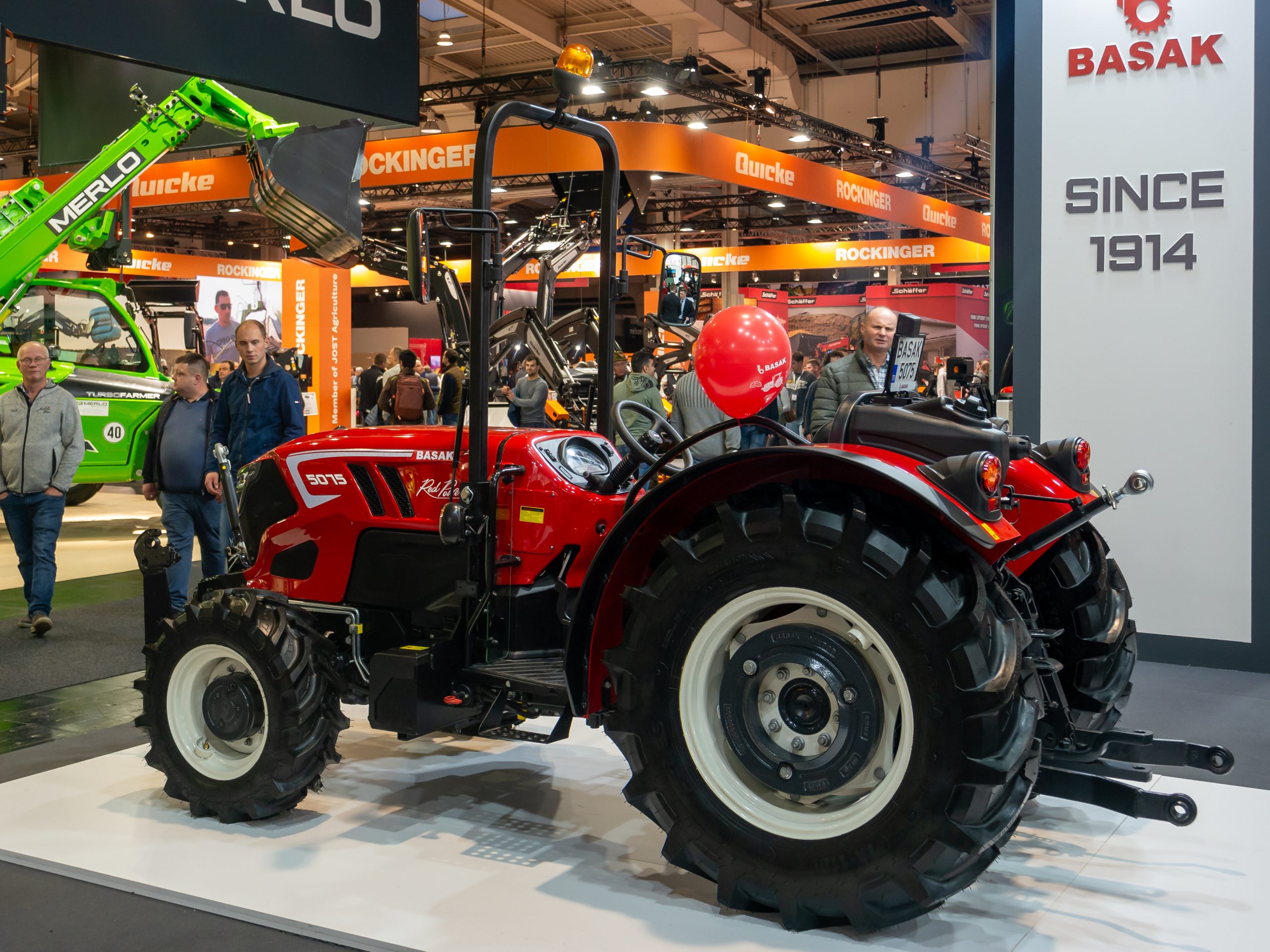 Polski traktor na zielonym polu uprawnym, w tle wiatraki, symbolizujące wyzwania i perspektywy polskiego rolnictwa w kontekście Zielonego Ładu UE.