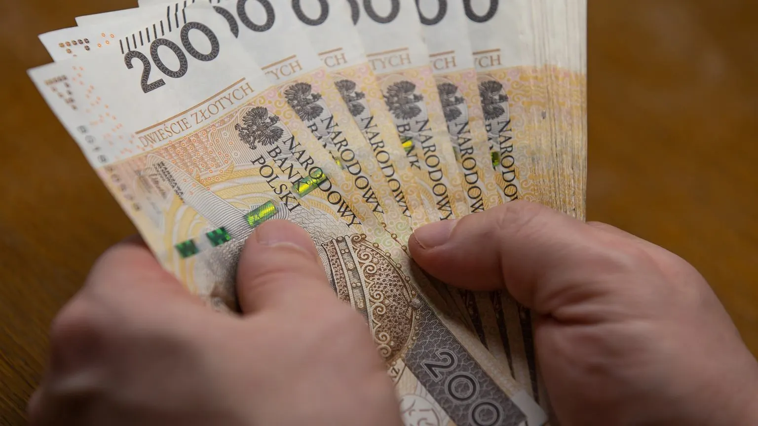 Zdjęcie przedstawiające stolarza precyzyjnie obrabiającego drewno w warsztacie stolarskim.