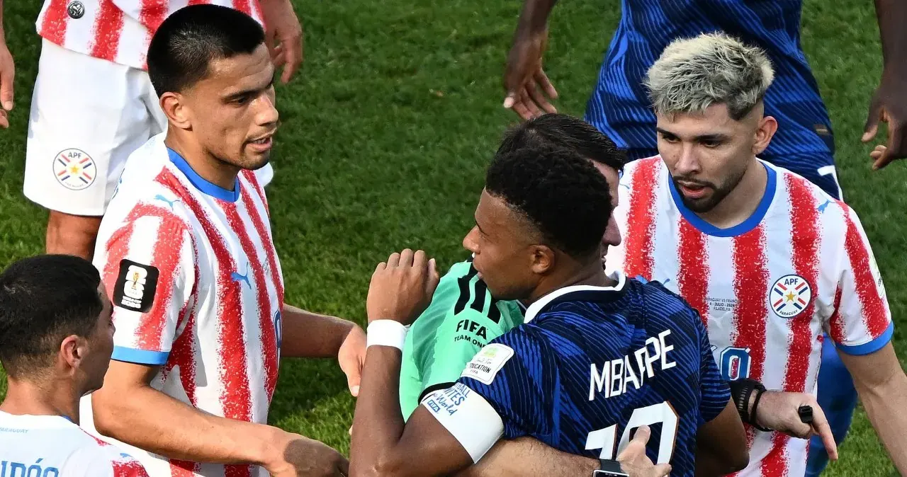 Kylian Mbappe podczas meczu Mistrzostw Świata, otoczony przez zawodników Paragwaju, widać napięcie na boisku