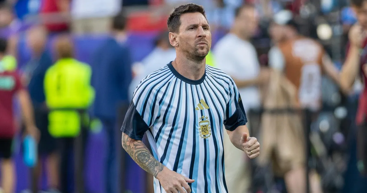 Leo Messi wpatrzony w dal, ubrany w koszulkę reprezentacji Argentyny, na tle stadionu piłkarskiego podczas Mistrzostw Świata.
