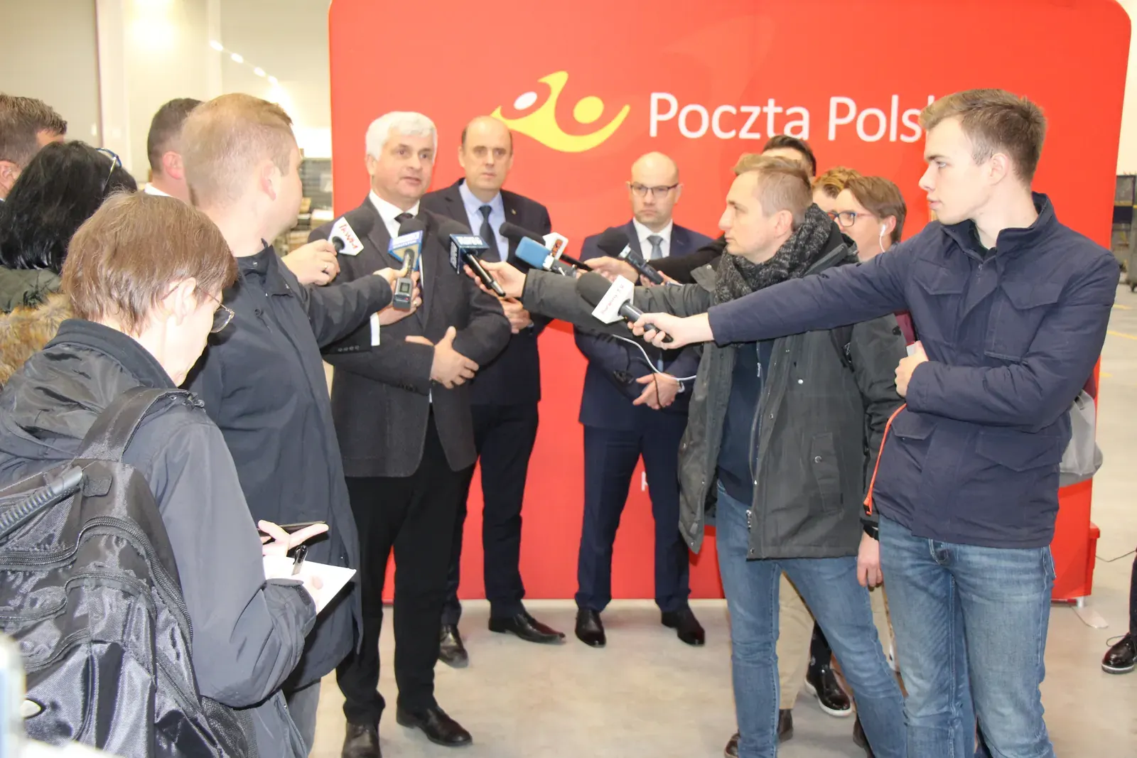 Wiceminister cyfryzacji Dariusz Standerski na konferencji prasowej o gigafabrykach AI, w tle wizualizacja infrastruktury obliczeniowej
