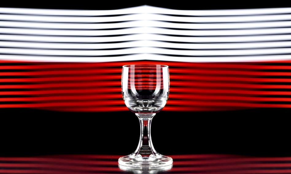 Klient w sklepie spożywczym ogląda napoje bezalkoholowe, w tle regały z wodą mineralną i sokami owocowymi