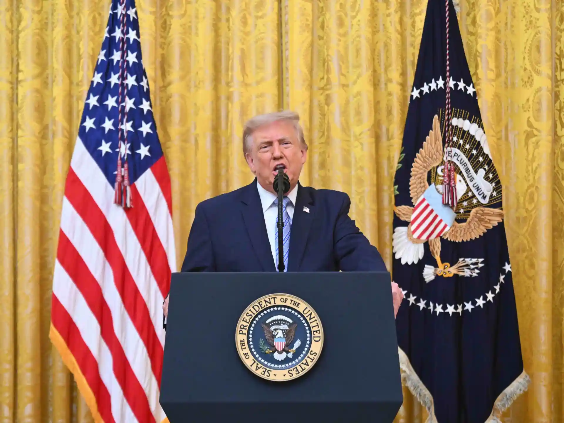 Donald Trump przemawia, w tle flaga Stanów Zjednoczonych.