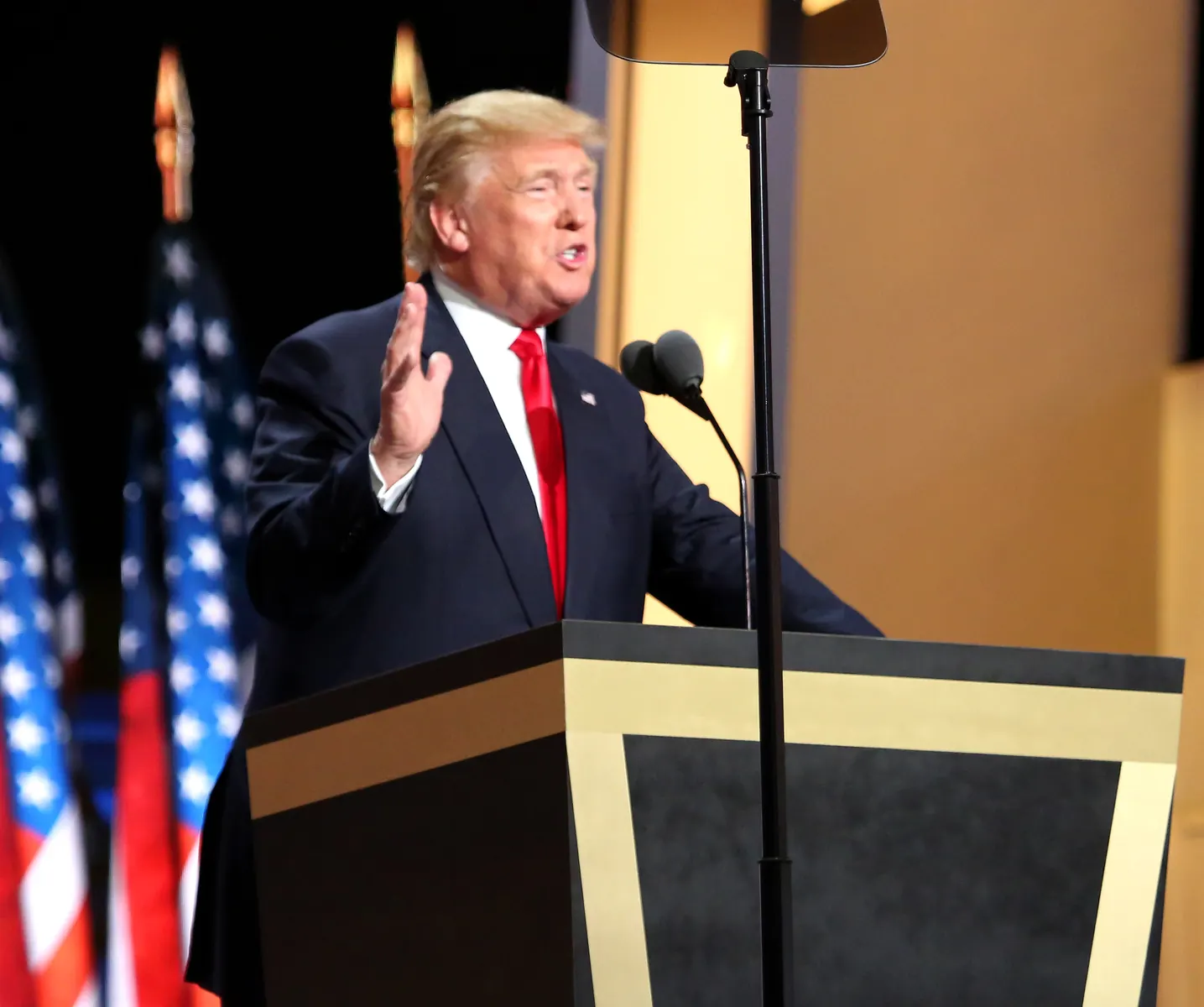 Donald Trump w tle z flagą Iranu symbolizującą napięcia dyplomatyczne.