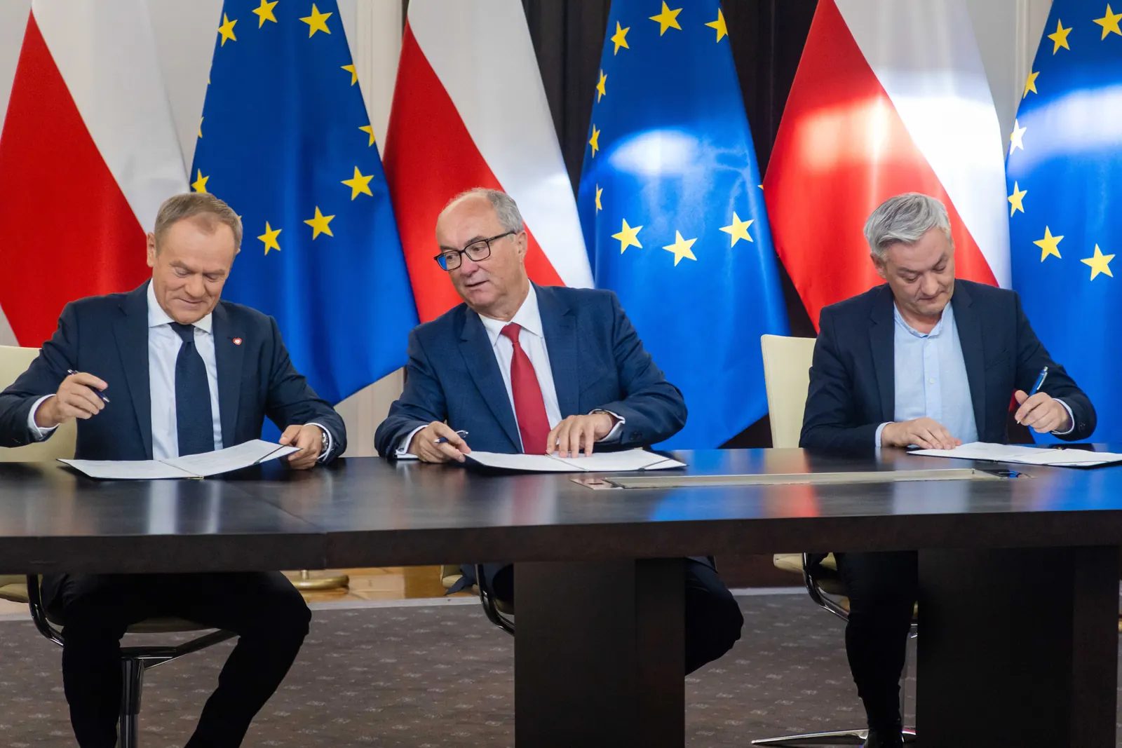 Ilustracja przedstawiająca dłonie podpisujące dokumenty na tle otwartego Kodeksu Pracy, symbolizująca zmiany prawne w 2024 roku.
