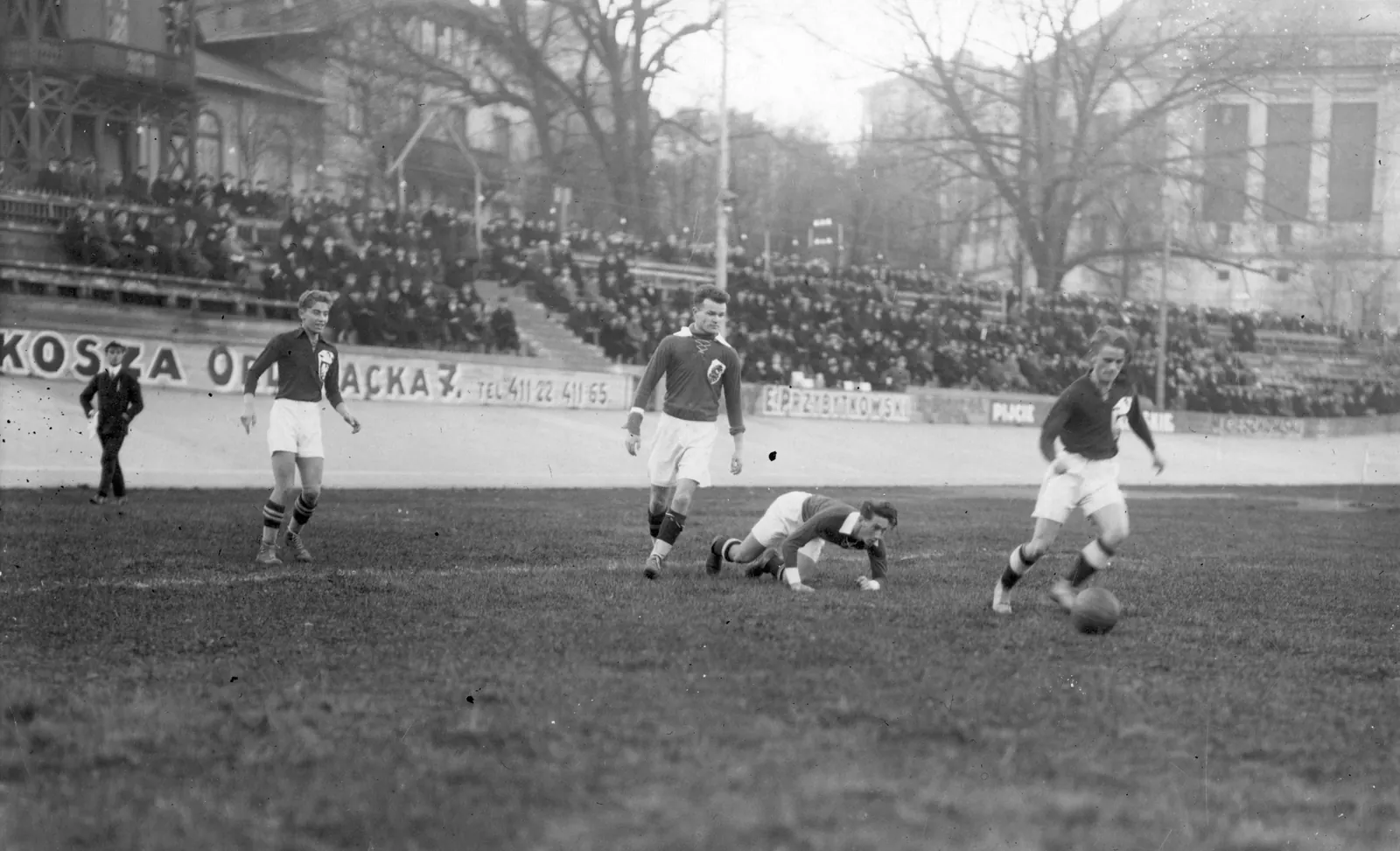 Piłkarze na boisku podczas przerwy na nawodnienie, wokół nich rozgrzani kibice na stadionie.