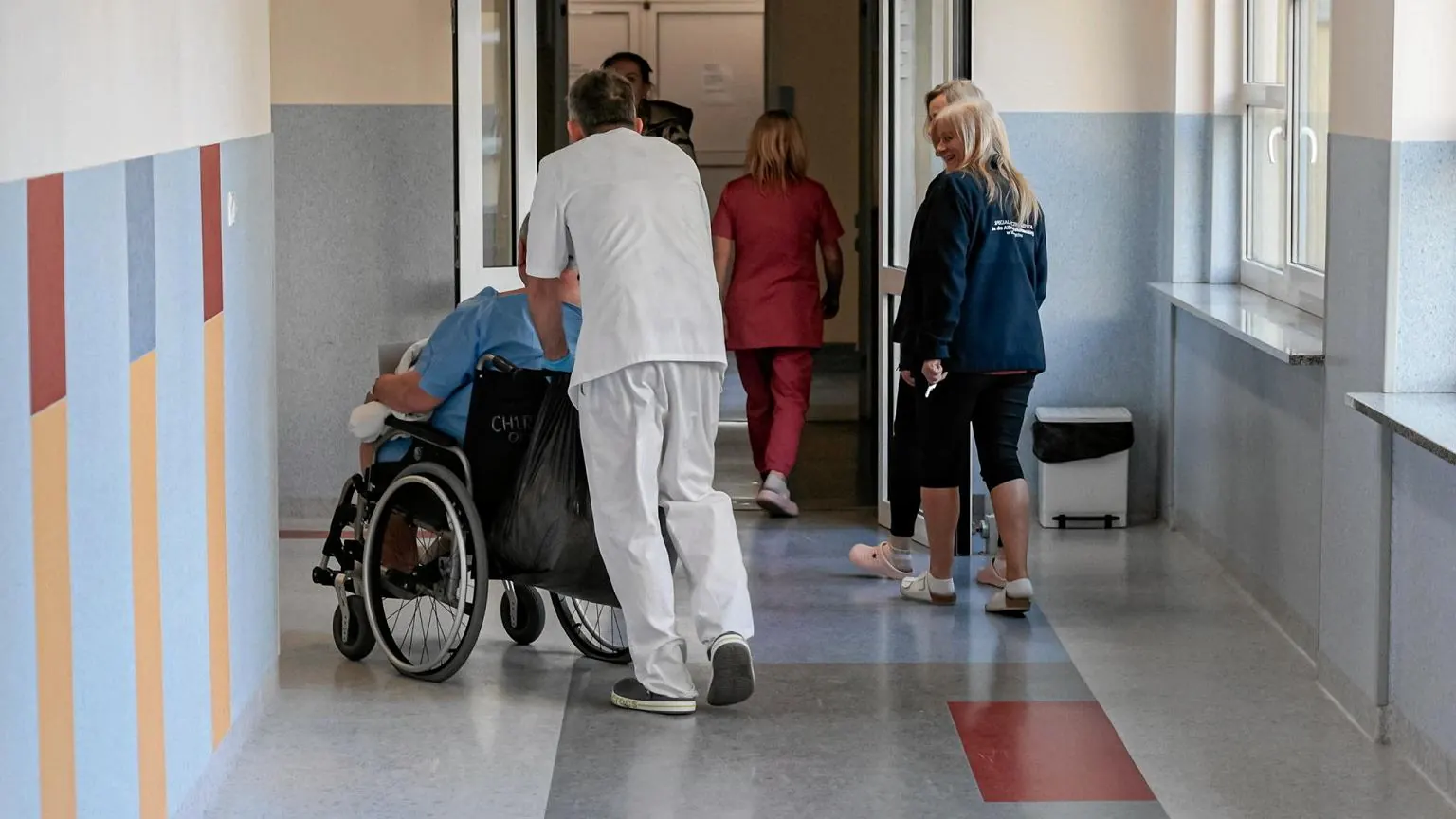 Lekarz w kitlu, rozmawiający z pacjentem w gabinecie.